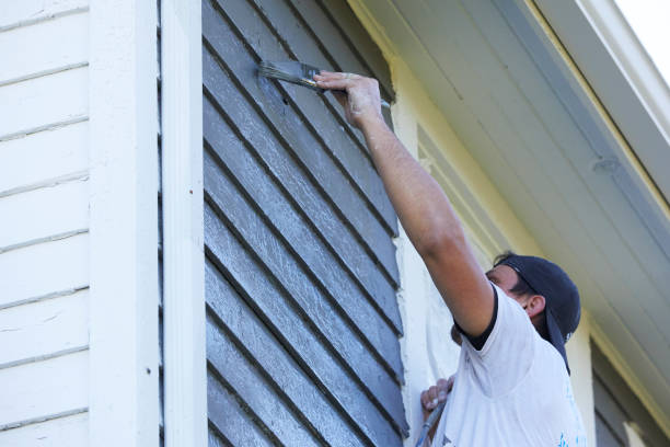 istock Man Brushing Paint On Exterior of Old Home 1047699122