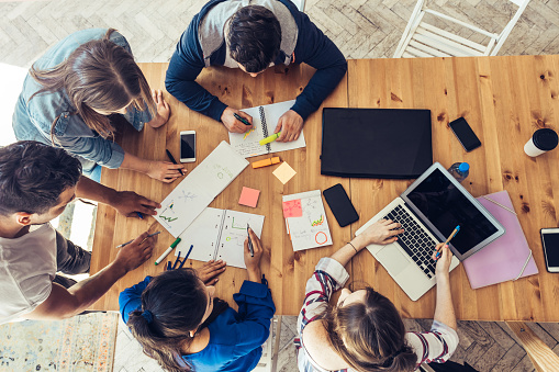 overhead view on young business people around wooden desk