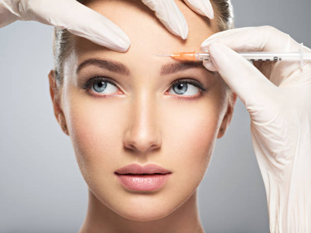 donna che si inietta botox cosmetico in fronte - attractive female human collagen syringe injecting foto e immagini stock