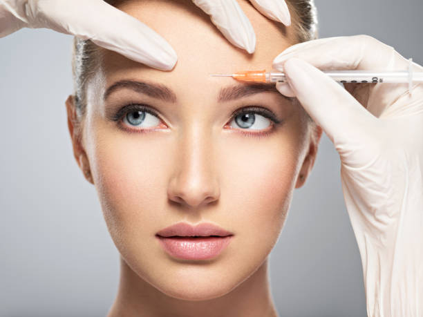 woman getting cosmetic botox injection in forehead Portrait of young Caucasian woman getting botox cosmetic injection in forehead. Beautiful woman gets botox injection in her face. forehead photos stock pictures, royalty-free photos & images