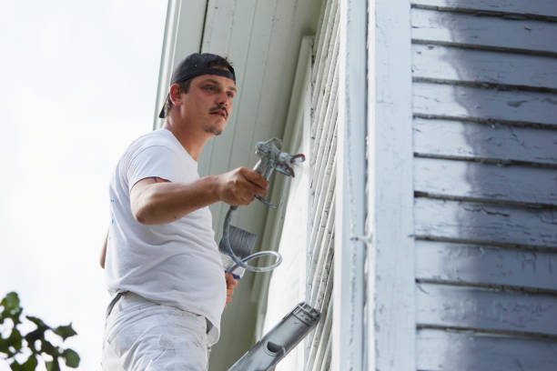 istock Man Spraying Paint On Exterior of Old Home 1047706586
