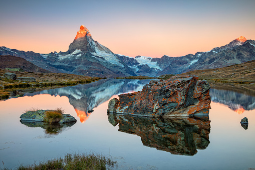 Landscape image of Swiss Alps with Stellisee and Matterhorn in the background during sunrise.