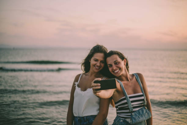 istock Young multi-ethnic hipster friends taking selfies at the beach 1047707308