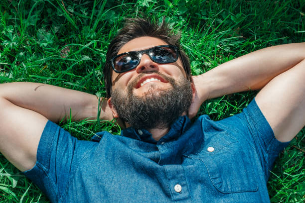 istock Smiling young man lying, dreaming and relaxing on green grass 1047710750