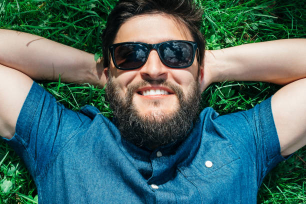 istock Smiling young man lying, dreaming and relaxing on green grass 1047710776