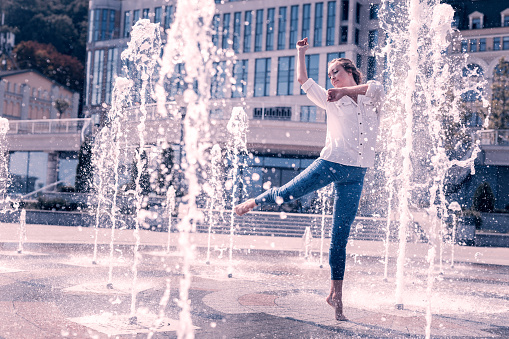 Power of water. Joyful nice woman standing in the fountain while dancing