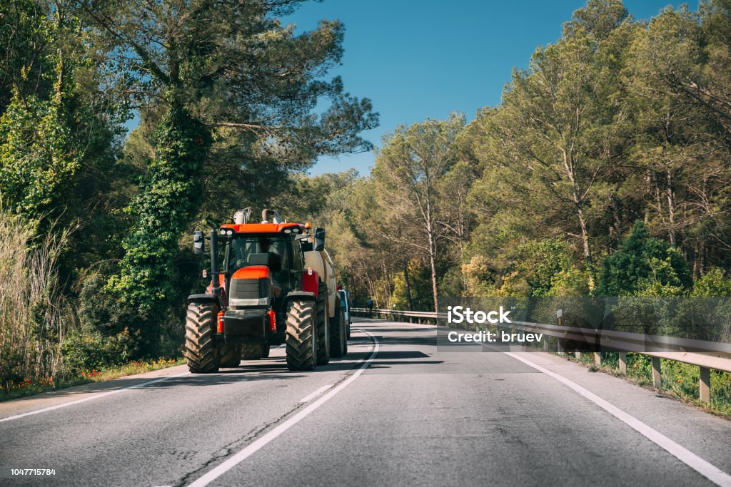 Tractor con aplicador de fertilizante con el tanque en movimiento en carretera en Europa. - Foto de stock de Tractor libre de derechos