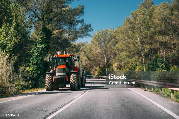 Tractor With Fertilizer Applicator With Tank In Motion On Country Road In Europe Stock Photo - Download Image Now