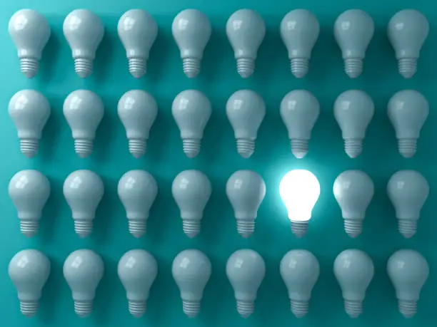 Photo of One glowing light bulb standing out from the unlit or dim bulbs on dark green pastel color background individuality and think different the business creative idea concepts 3D rendering