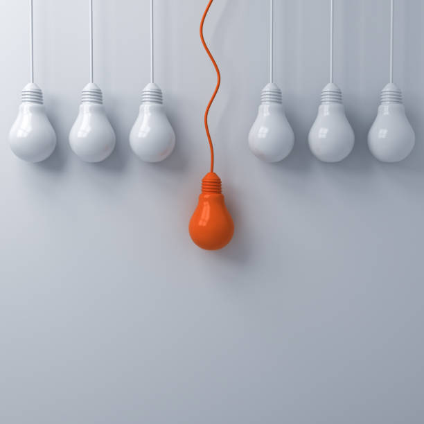 istock Think different concept One hanging orange light bulb standing out from the dim unlit white light bulbs on white wall background leadership and individuality creative idea concepts 3D rendering 1047719524