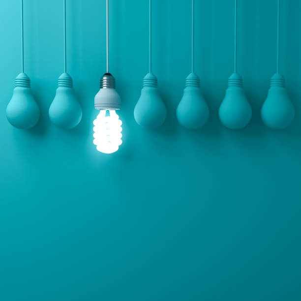 One hanging eco energy saving light bulb glowing and standing out from unlit incandescent bulbs on dark green pastel color wall background leadership and different creative idea concepts 3D rendering