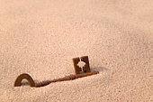 Rusty old key in sand