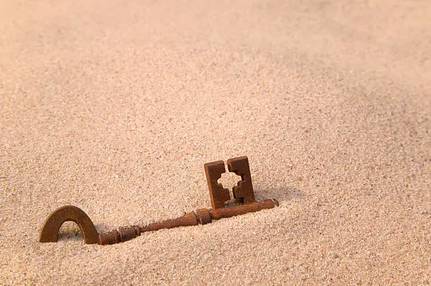 Photo of Rusty old key in sand