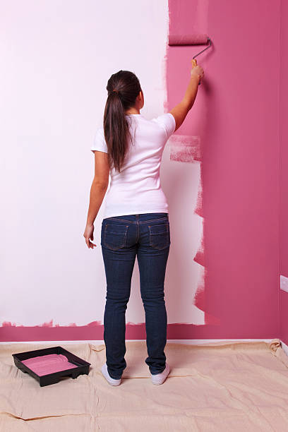 Woman painting a wall rear view stock photo