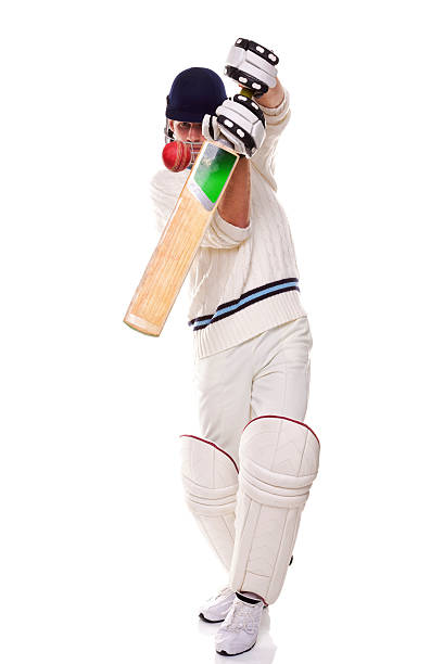Young cricket sport player wears helmet and gloves, holding cricket bat and old cricket ball in outdoor field, soft focus, hobbies and education concept.