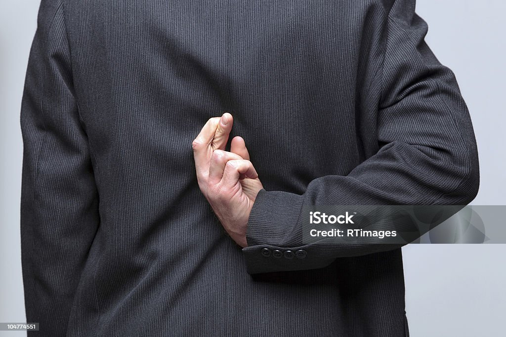 Businessman fingers crossed behind his back Businessman with his fingers crossed behind his back, Adult Stock Photo