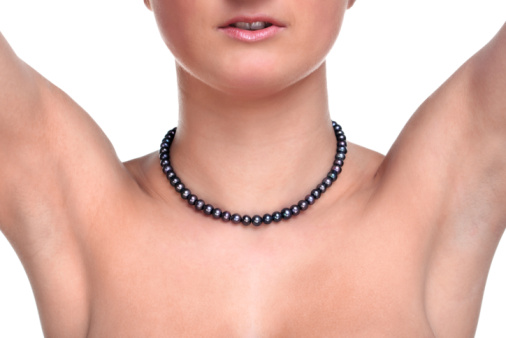 Close up photo of a woman wearing a black pearl necklace, white background.