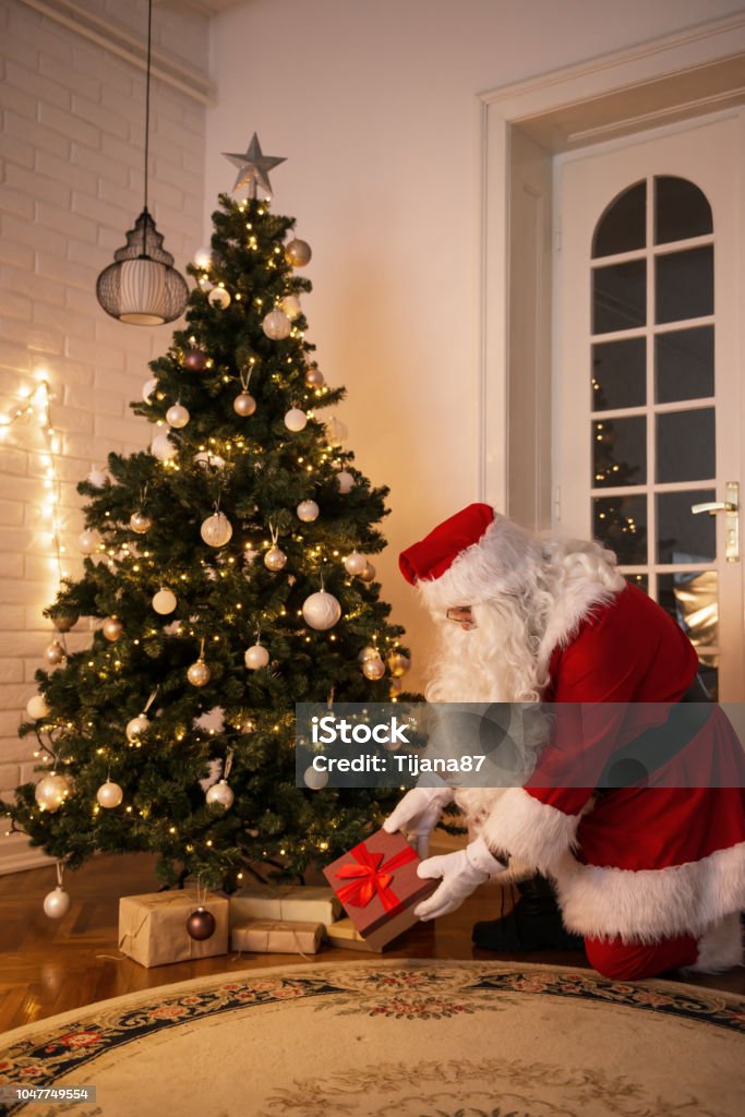 Foto de Papai Noel Deixando Um Presente Debaixo Da Árvore De Natal Na Noite  De Natal e mais fotos de stock de Papai Noel - iStock