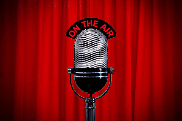 istock Microphone on stage with spotlight against a red curtain 104774956