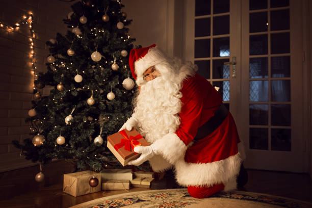 istock Santa Claus leaving a present under the Christmas tree on Christmas evening 1047749704