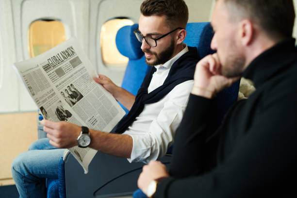 istock Business People Reading Newspaper in Plane 1047752956