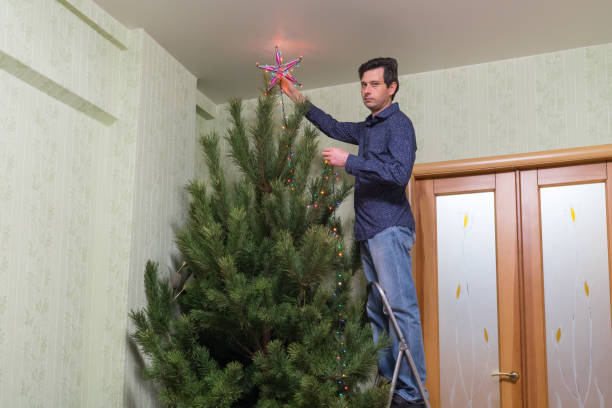 istock Handsome middle-aged man decorates a Christmas tree with a star 1047757012