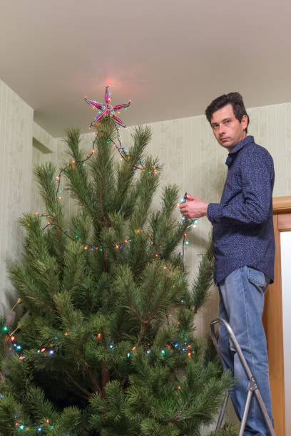 istock Handsome middle-aged man decorates a Christmas tree with a star 1047757142