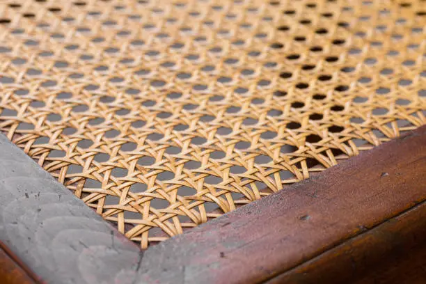 Close up of the pattern formed by open weave rattan cane on a chair seat
