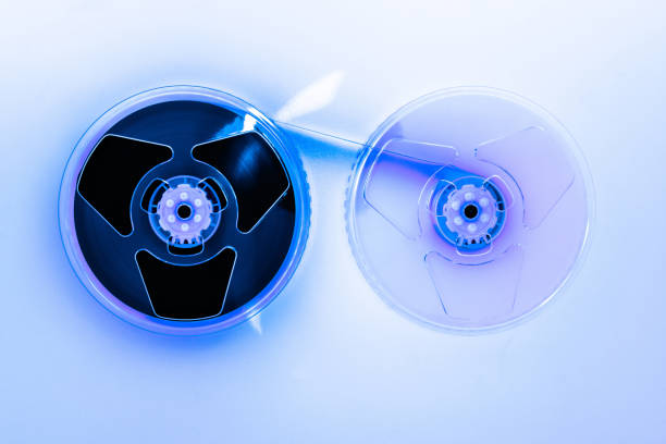 istock Abstract composition of video home system VHS tape reels illuminated with blue light and placed on white background 1047757594