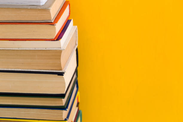 istock Stack of shabby books in library on yellow background 1047771948