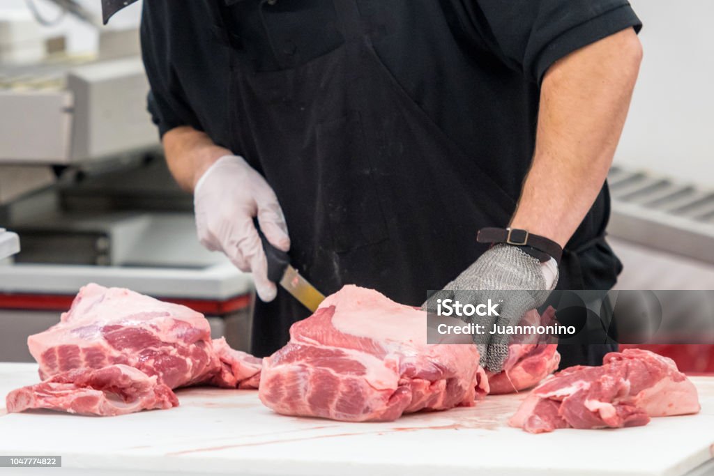 Butcher at work unrecognizable male butcher preparing raw meat Butcher's Shop Stock Photo