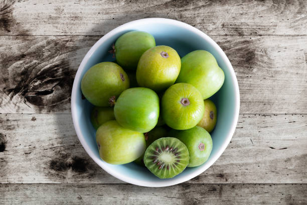 frutas de quivi résistentes ou quivi bagas actinidia arguta na tigela de cerâmica - actinidia - fotografias e filmes do acervo