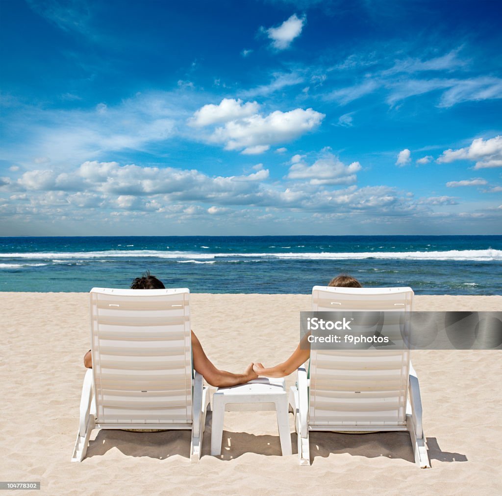 Paar auf Liegestühlen holding Hände in der Nähe von Meer - Lizenzfrei Dating Stock-Foto