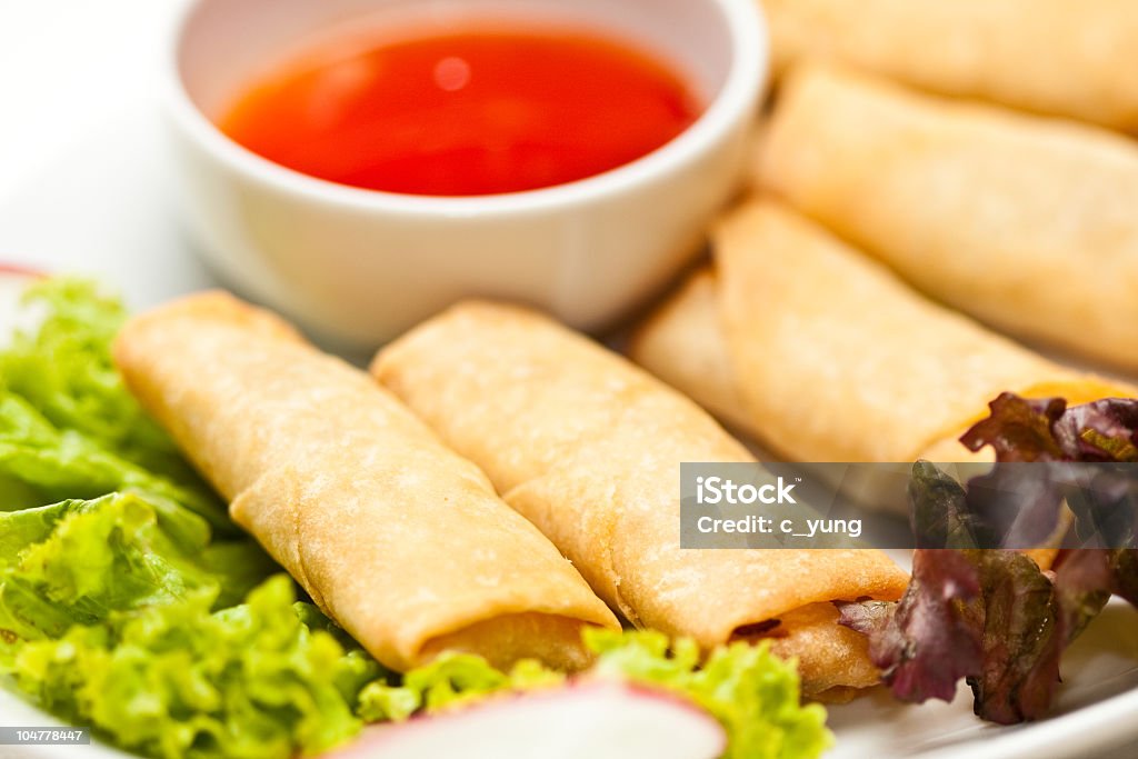 Plate with five fried eggrolls, lettuce and a bowl of sauce  mini vegetarian eggrolls with salad and chili sweet sour sauce closeup Appetizer Stock Photo