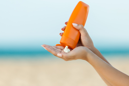 Mano de mujer aplicar protector solar en la playa photo