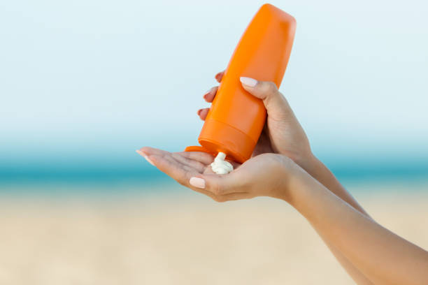 Woman hand apply sunscreen on the beach Woman hand apply sunscreen on the beach tan skin stock pictures, royalty-free photos & images