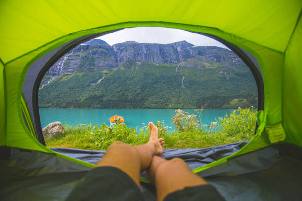 istock Mans feet viewed from inside tent by blue lake in Norway. 1047798548