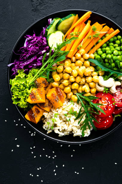 istock Bowl dish with brown rice, cucumber, tomato, green peas, red cabbage, chickpea, fresh lettuce salad and cashew nuts. Healthy balanced eating 1047798564