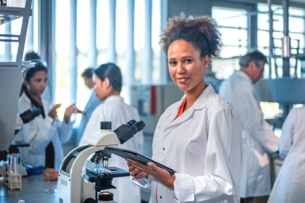 scienziato sorridente con tablet digitale in laboratorio - research smiling scientist women foto e immagini stock