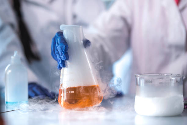 Scientist holding flask with evaporating liquid Close-up of scientist holding flask with evaporating liquid. Researcher is doing experiment in laboratory and is wearing gloves. chemical reaction stock pictures, royalty-free photos & images