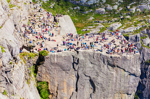 PREIKESTOLEN, NORWAY - JULY 23, 2017: Tourists at Preikestolen or Prekestolen or Pulpit Rock, famous tourist attraction near Stavanger, Norway. Preikestolen is a cliff, rises above Lysefjord.