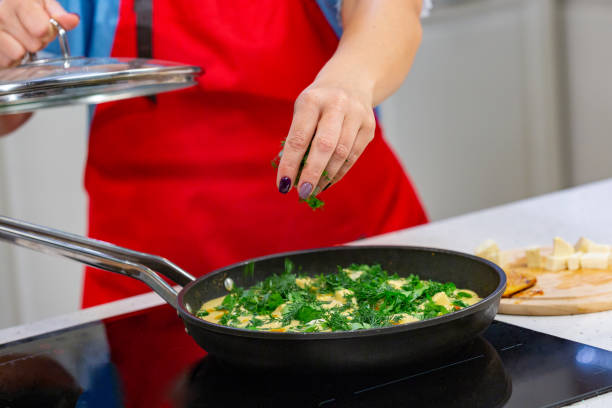 istock woman chef preparing omelette with herbs at a kitchen. Hands close up 1047810564