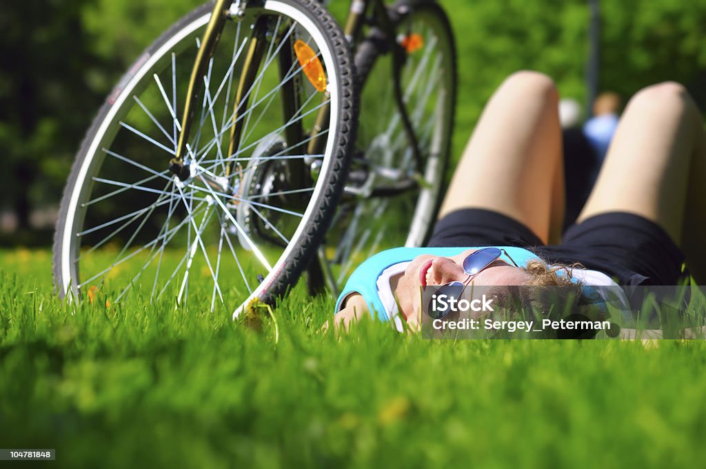 Женщина лежа рядом с ее велосипед - Стоковые фото 20-24 года роялти-фри