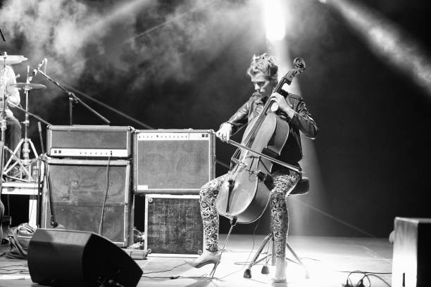 Woman playing cello on the stage Young female musician playing cello on stage in black and white. violinist photos stock pictures, royalty-free photos & images