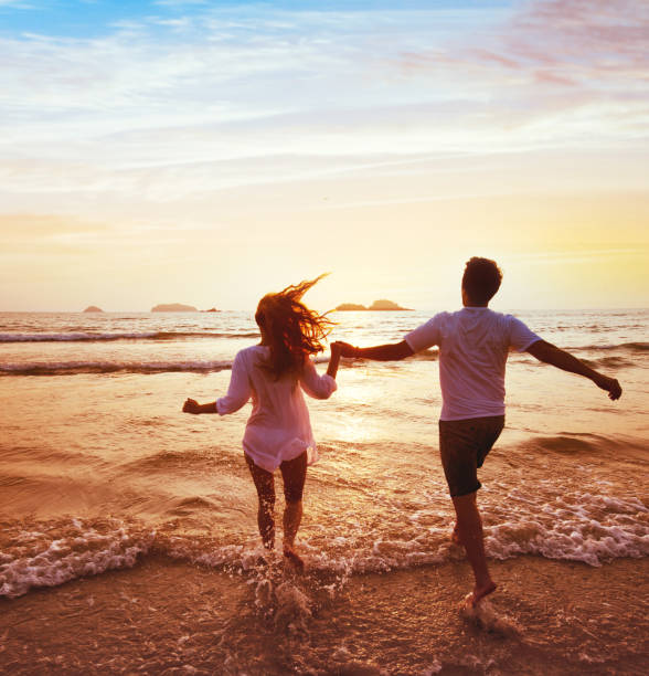 happy couple on honeymoon vacation travel, beach holidays happy couple on honeymoon vacation travel, romantic dream beach holidays, happiness background, silhouettes of man and woman running to the sea at sunset together honeymoon stock pictures, royalty-free photos & images