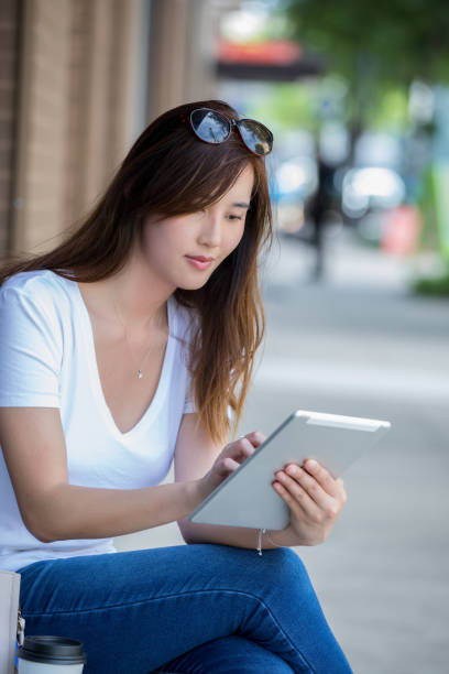 istock Asian woman using digital tablet outdoors in city 1047840490