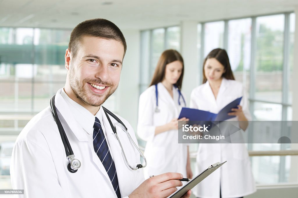 Young doctor A portrait of doctor with two attractive nurses in the background Adult Stock Photo
