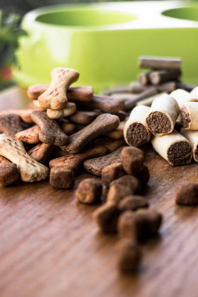istock Dog tasty colored biscuits on wooden background, bowl 1047844892