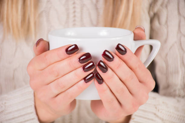 Woman with brown nails polish holds cup of coffee in hands stock photo
