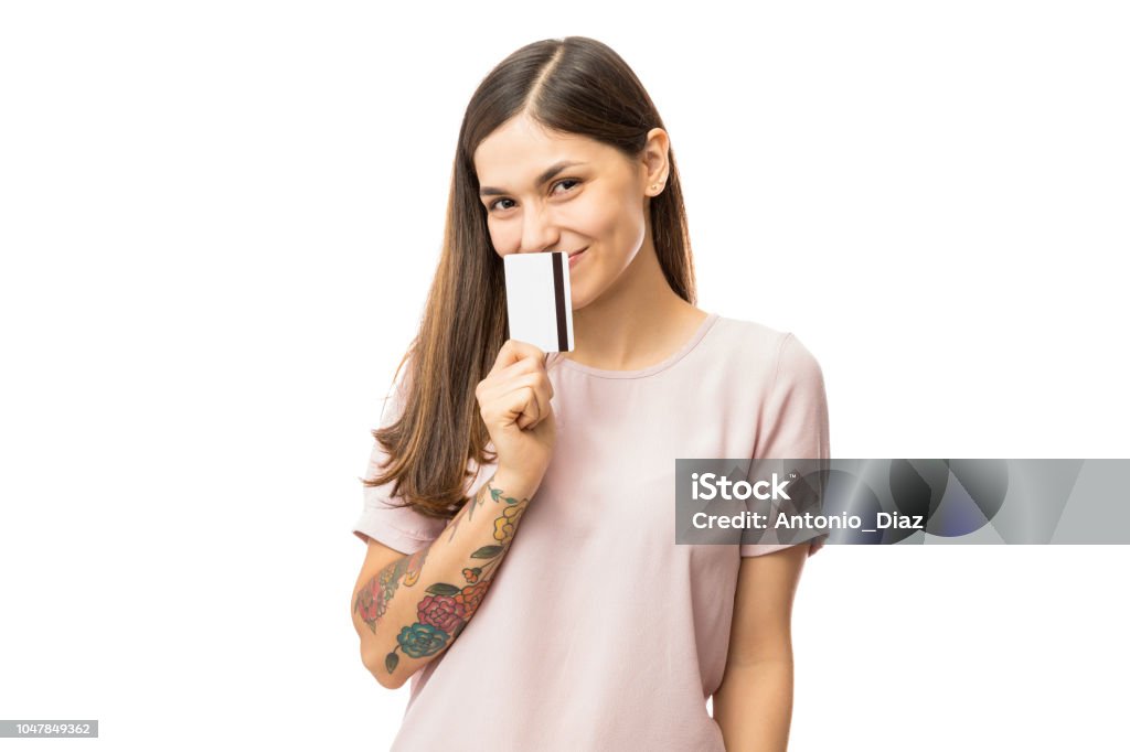 Happy Young Woman Covering Mouth With Credit Card Happy young woman covering mouth with credit card over white background Credit Card Stock Photo